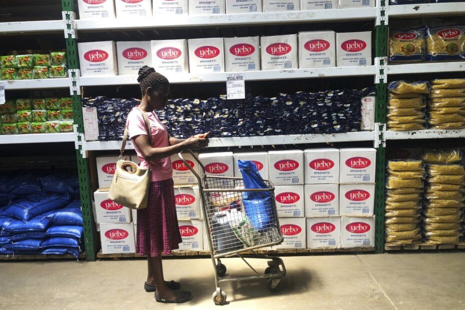 A woman does a quick calculation on her phone before buying groceries at a shop in Harare, in this Wednesday, Oct, 9, 2019 photo. Hyperinflation is changing prices so quickly in the southern African nation that what you would see displayed on a supermarket shelf might change by the time you reach the checkout. (AP Photo/Tsvangirayi Mukwazhi)